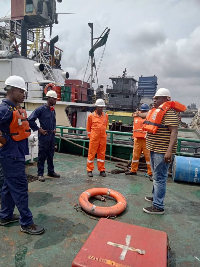Crew in orange coveralls and life jackets gathered on deck for a briefing