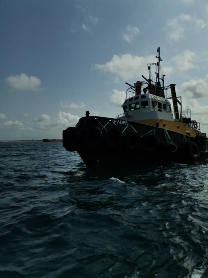 A black tug under a blue sky on open water