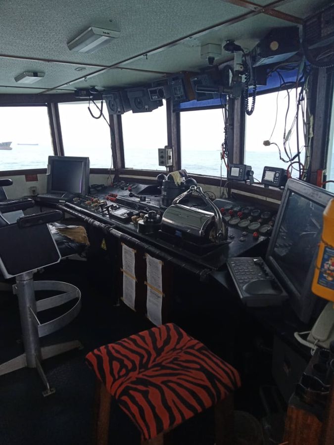 Crew in orange coveralls on deck with a lifebuoy and hard hats